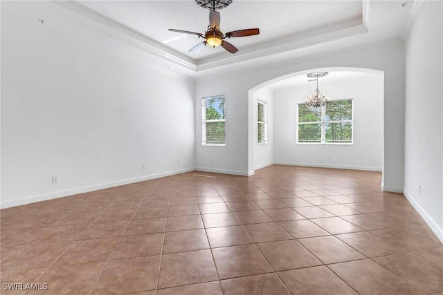 spare room featuring arched walkways, a healthy amount of sunlight, tile patterned flooring, and a raised ceiling