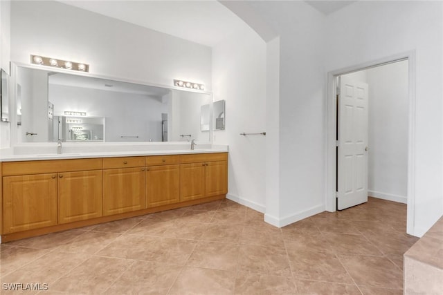 bathroom featuring double vanity, a sink, and baseboards
