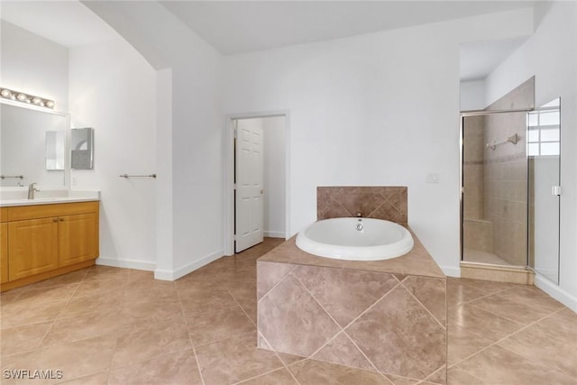 bathroom featuring a stall shower, vanity, tile patterned flooring, a bath, and baseboards