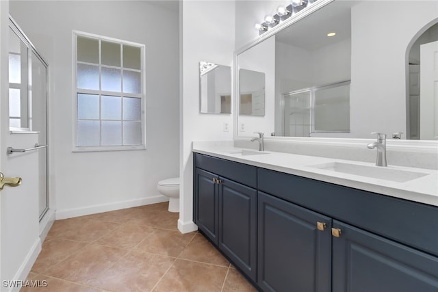 bathroom with tile patterned floors, a shower with door, vanity, and toilet