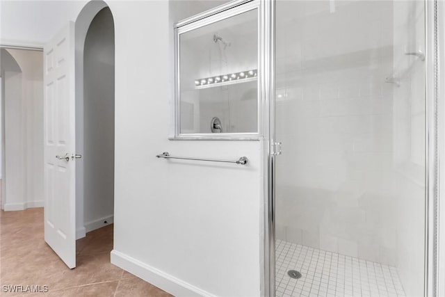 bathroom with tile patterned floors, baseboards, and a shower stall