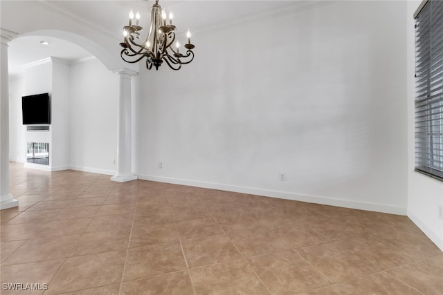 spare room with a notable chandelier, ornamental molding, light tile patterned floors, and ornate columns