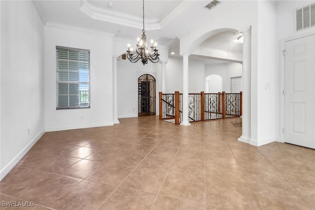 tiled empty room featuring an inviting chandelier, a raised ceiling, crown molding, and ornate columns