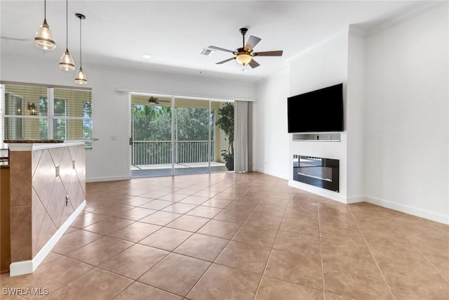 unfurnished living room featuring a glass covered fireplace, light tile patterned floors, baseboards, visible vents, and ceiling fan