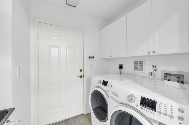 laundry room featuring cabinets, light wood-type flooring, and washing machine and clothes dryer