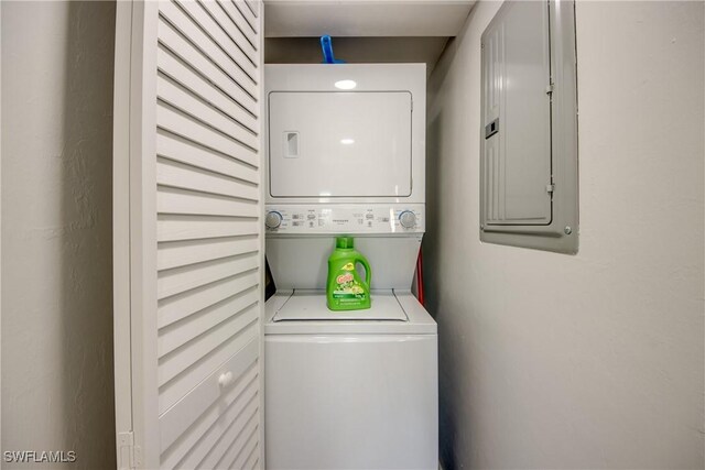 clothes washing area with stacked washer and clothes dryer and electric panel