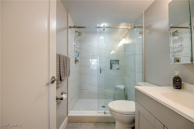 bathroom with vanity, toilet, tile patterned floors, and a shower with door