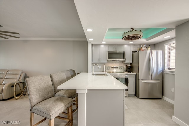 kitchen with ceiling fan, sink, gray cabinets, appliances with stainless steel finishes, and a kitchen breakfast bar