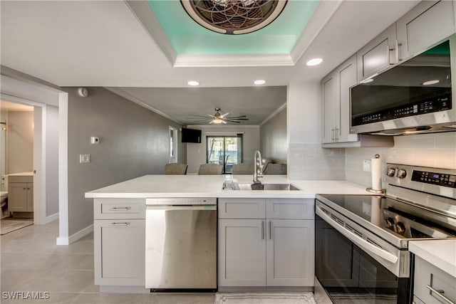 kitchen with gray cabinetry, kitchen peninsula, ceiling fan, and stainless steel appliances