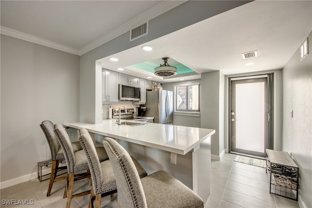 kitchen featuring ornamental molding, stainless steel appliances, kitchen peninsula, and a breakfast bar