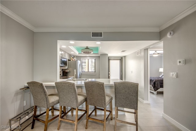 dining area with crown molding and light tile patterned floors