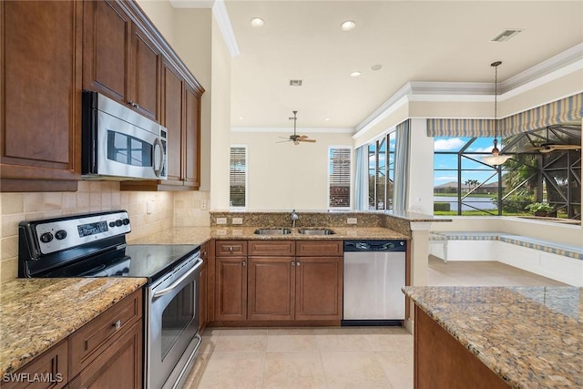 kitchen with sink, crown molding, backsplash, stainless steel appliances, and decorative light fixtures