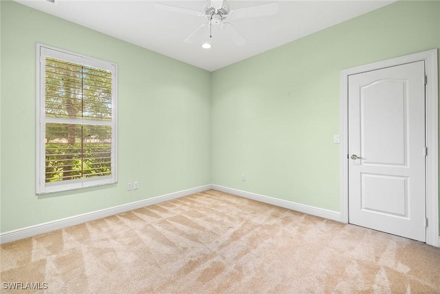 spare room with light colored carpet and ceiling fan