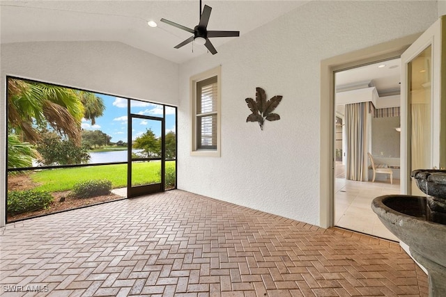 unfurnished sunroom with lofted ceiling, ceiling fan, and a water view