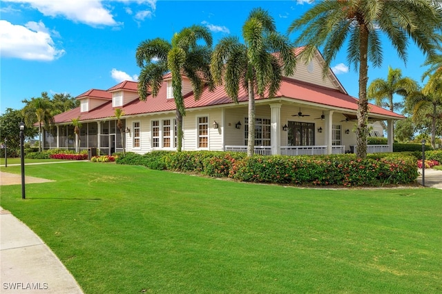 farmhouse-style home with ceiling fan, a sunroom, and a front lawn