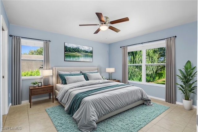 bedroom featuring multiple windows, light tile patterned flooring, and ceiling fan