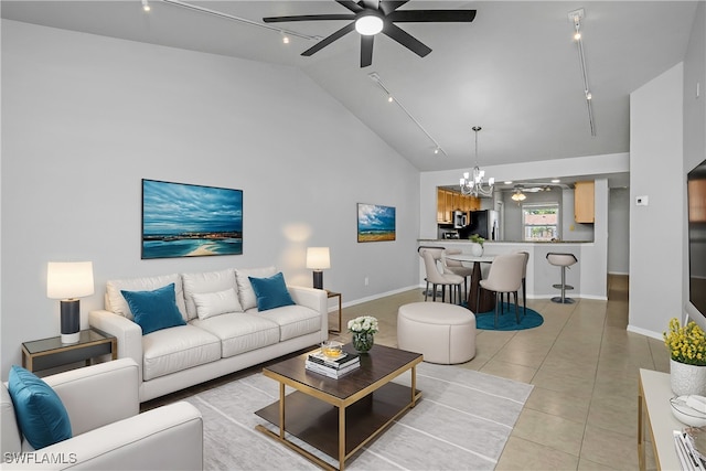 tiled living room with ceiling fan with notable chandelier, high vaulted ceiling, and rail lighting