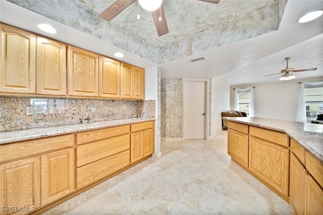 kitchen featuring ceiling fan, light brown cabinets, light stone counters, and tasteful backsplash