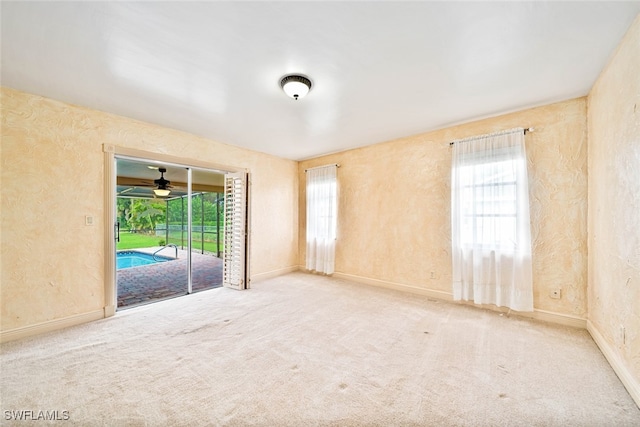 spare room featuring light carpet, ceiling fan, and a healthy amount of sunlight