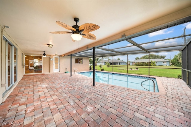 view of swimming pool with glass enclosure, a yard, ceiling fan, and a patio area