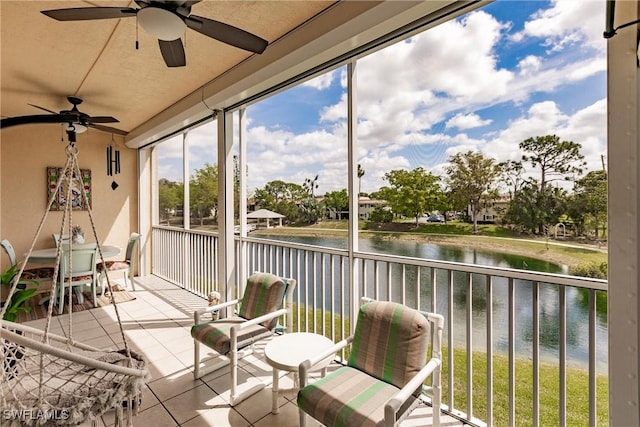 sunroom with a water view and ceiling fan