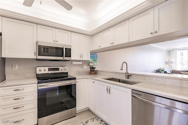 kitchen featuring ornamental molding, a sink, stainless steel appliances, light wood finished floors, and ceiling fan