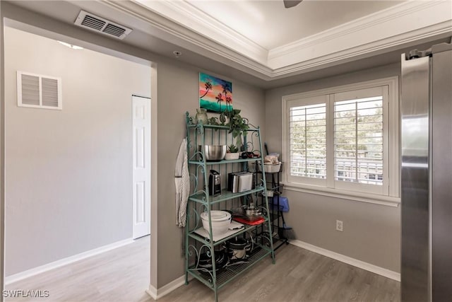 interior space with visible vents, baseboards, wood finished floors, and crown molding