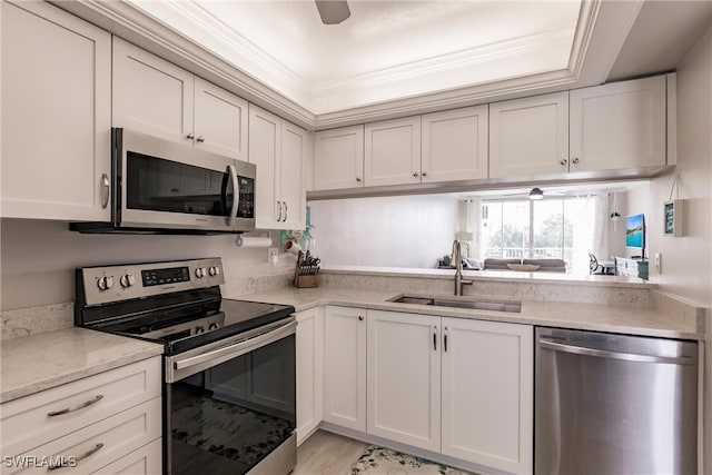 kitchen with appliances with stainless steel finishes, white cabinetry, crown molding, and a sink