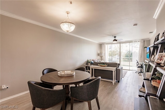 dining space with light wood-type flooring, baseboards, crown molding, and ceiling fan with notable chandelier