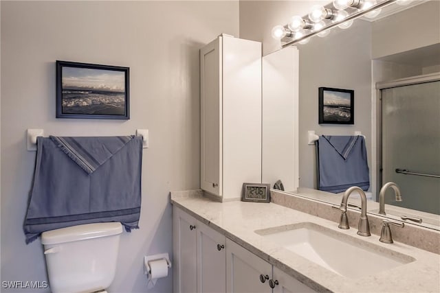 bathroom with a shower with shower door, toilet, and vanity