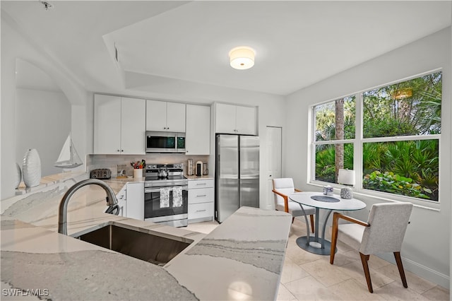 kitchen featuring light stone countertops, stainless steel appliances, sink, and white cabinetry