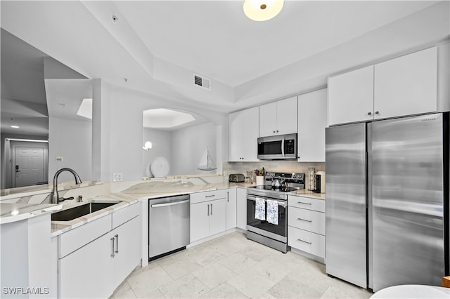 kitchen featuring light stone counters, appliances with stainless steel finishes, sink, and white cabinetry