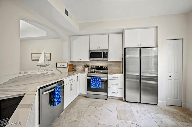 kitchen with light stone counters, white cabinets, appliances with stainless steel finishes, and kitchen peninsula