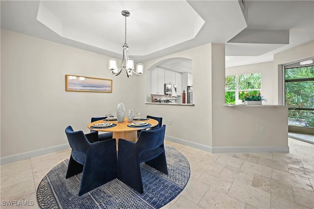 dining area featuring an inviting chandelier and a raised ceiling