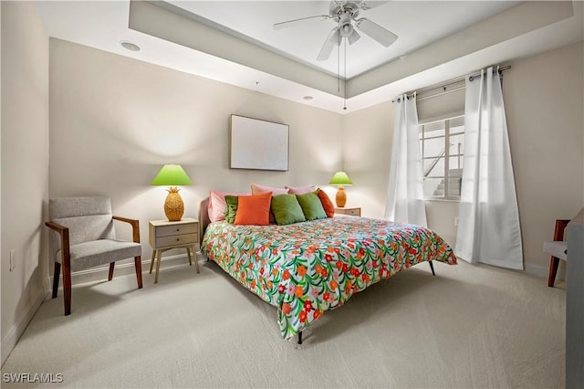 bedroom featuring ceiling fan, light colored carpet, and a raised ceiling