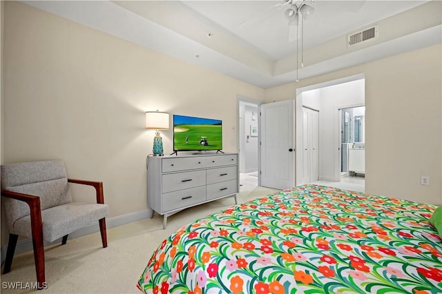 bedroom with light carpet, ceiling fan, and a raised ceiling