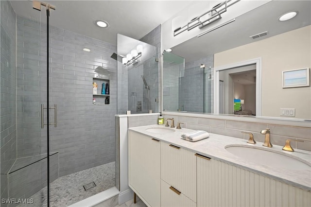 bathroom with vanity, decorative backsplash, and a shower with door