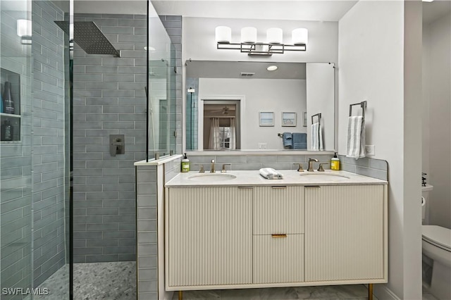 bathroom featuring toilet, tiled shower, and vanity