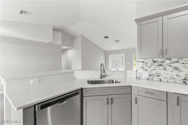 kitchen with gray cabinetry, vaulted ceiling, kitchen peninsula, dishwasher, and sink