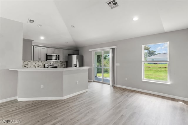 kitchen featuring gray cabinetry, lofted ceiling, appliances with stainless steel finishes, and plenty of natural light