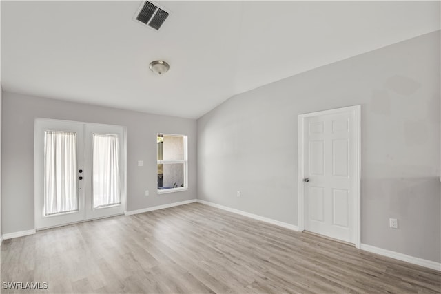 unfurnished room featuring french doors, light wood-type flooring, and vaulted ceiling