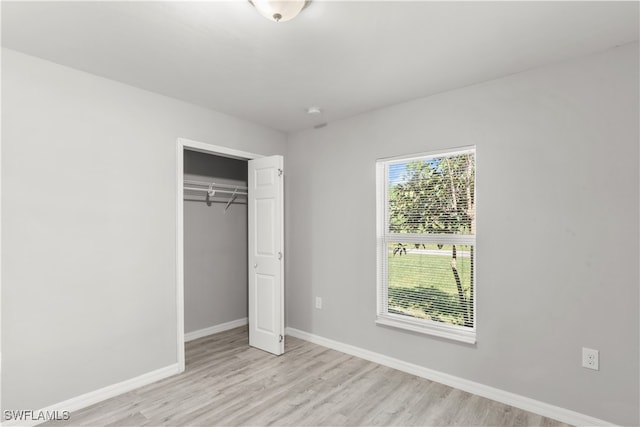 unfurnished bedroom with light wood-type flooring and a closet