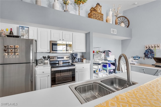 kitchen with stainless steel appliances, a towering ceiling, sink, and white cabinetry