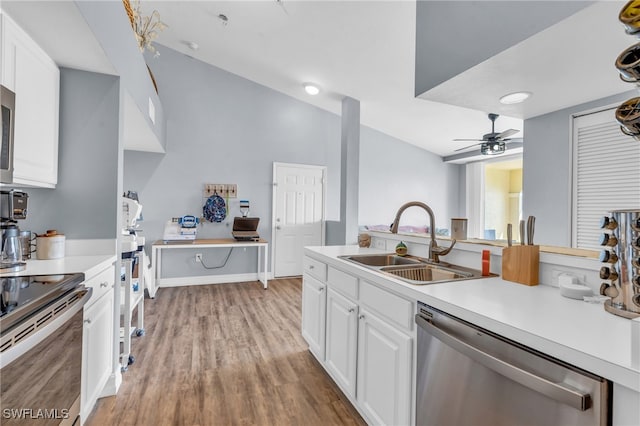 kitchen with appliances with stainless steel finishes, white cabinetry, sink, and light hardwood / wood-style flooring