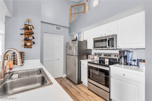 kitchen with light wood-type flooring, white cabinetry, sink, and stainless steel appliances