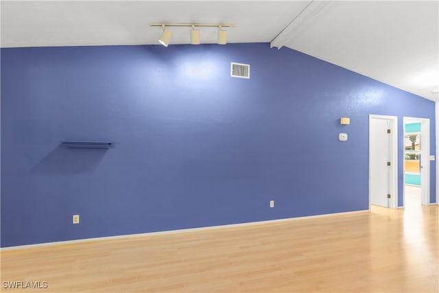 empty room featuring light wood-type flooring and lofted ceiling with beams