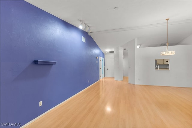 interior space with track lighting, hardwood / wood-style flooring, and vaulted ceiling