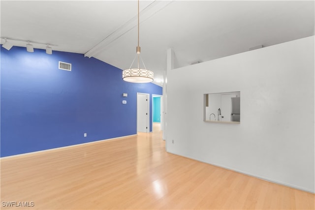 empty room with sink, beam ceiling, wood-type flooring, high vaulted ceiling, and rail lighting