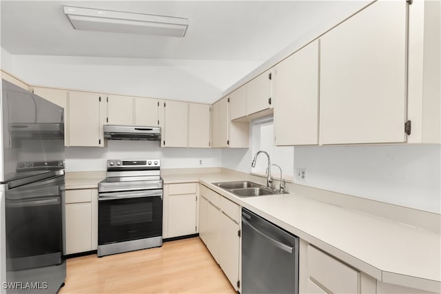 kitchen featuring appliances with stainless steel finishes, lofted ceiling, light wood-type flooring, and sink