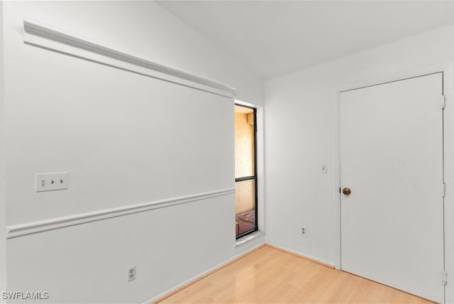 empty room featuring wood-type flooring and vaulted ceiling